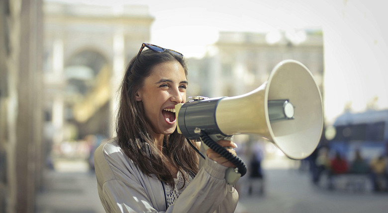 Foto door Andrea Piacquadio: https://www.pexels.com/nl-nl/foto/vrolijke-jonge-vrouw-die-in-megafoon-gilt-3761509/